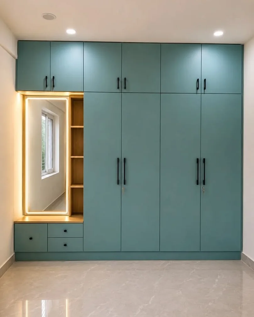 Floor-to-ceiling wardrobe with mirror, dresser and warm cove lighting.