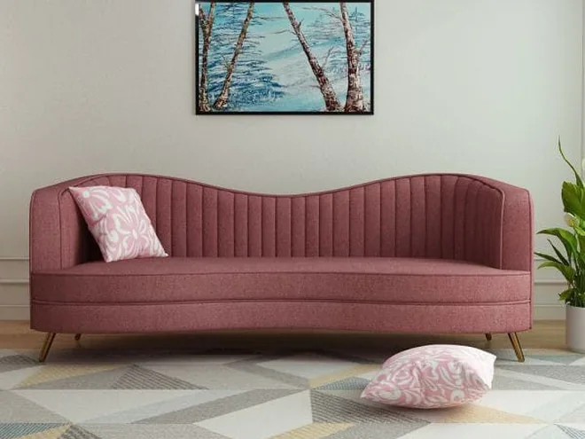 Dusty rose curved sofa with slim wooden legs.