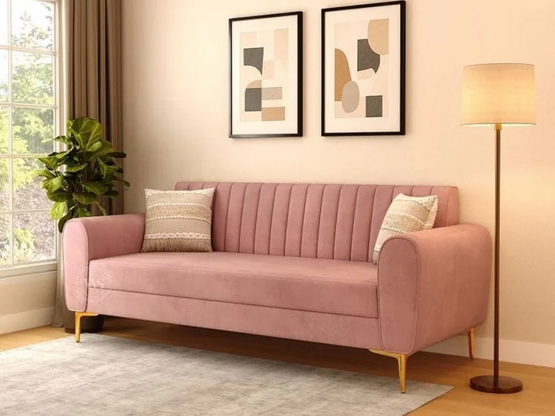 Pale pink three-seater sofa beside a floor lamp.